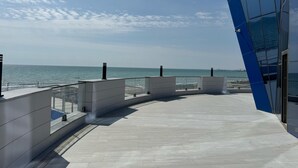 A modern building with a glass facade overlooking a beach. - TITANIK BAKU (Baku)