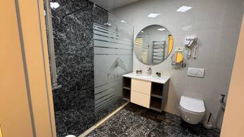 Een moderne badkamer met een marmeren vloer, een douchecabine met glazen wanden, een wastafel met spiegel, een toilet en een handdoekhouder.