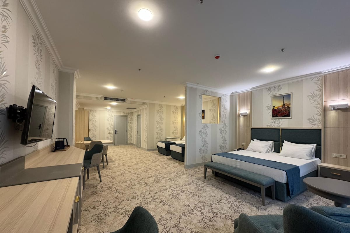 A hotel room with a bed, a desk, a chair, a TV, and a bathroom.