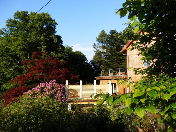 A wooden cabin with a balcony, surrounded by lush greenery and trees. - Kleine-Bastei.de 's highest-elevation vacation home, located in the popular spa town of Rathen. (Rathen)