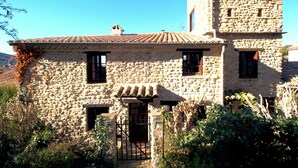 A stone building with a tiled roof, a small tower, and a gate. - La Maison Madeleine (Nyons)