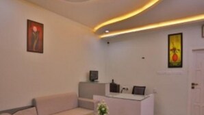A modern reception area with a sofa, a small table with a vase, and a reception desk. - Winter Garden Resorts (Munnar)