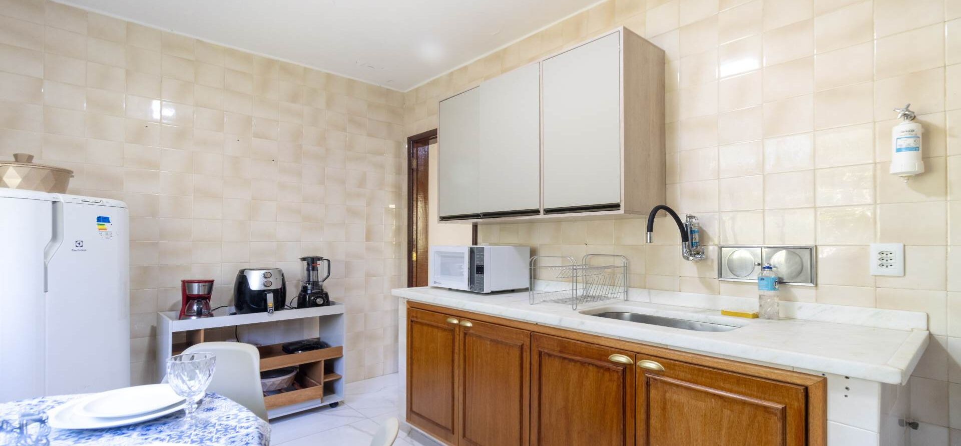A compact kitchen with a white refrigerator, a coffee maker, a microwave, and a sink.