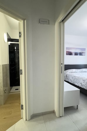 A modern bedroom with a bed, a bedside table, and a view of the outside. - In the Historic Centre, with a View of the Towers (Alba)