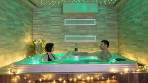 Een stel in een jacuzzi met LED-verlichting, omringd door stenen muren en een houten vloer.
