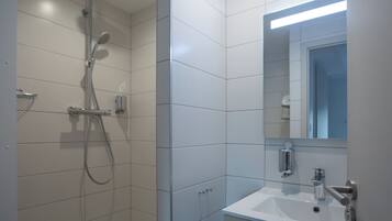 A modern bathroom with a shower, sink, and mirror.