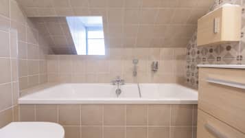 A bathroom with a bathtub, a toilet, and a wooden cabinet.
