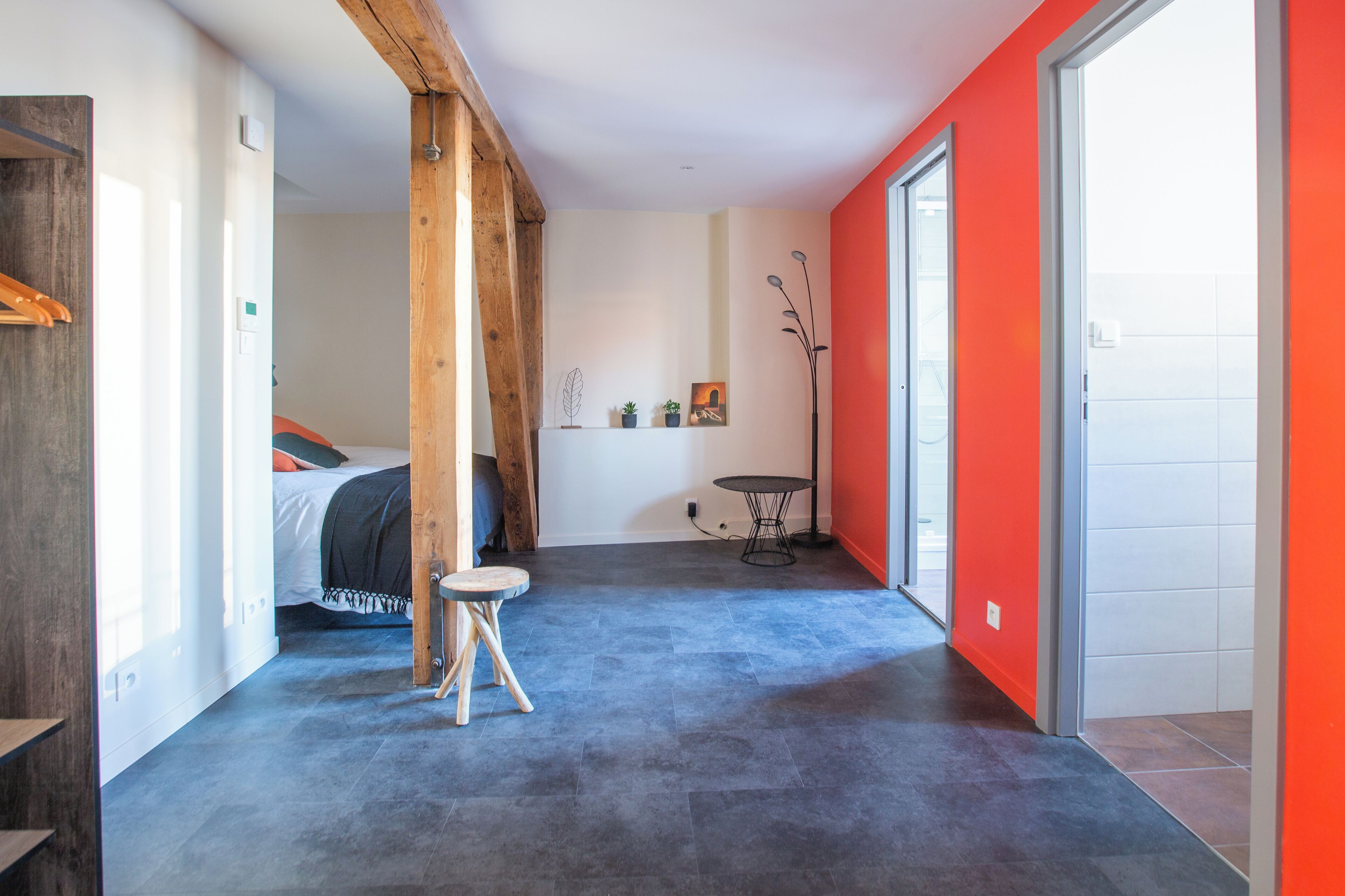 A modern room with a bed, a small round table, and a red accent wall.