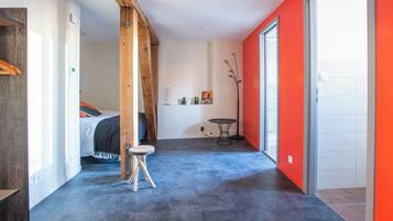 A modern room with a bed, a small round table, and a red accent wall.