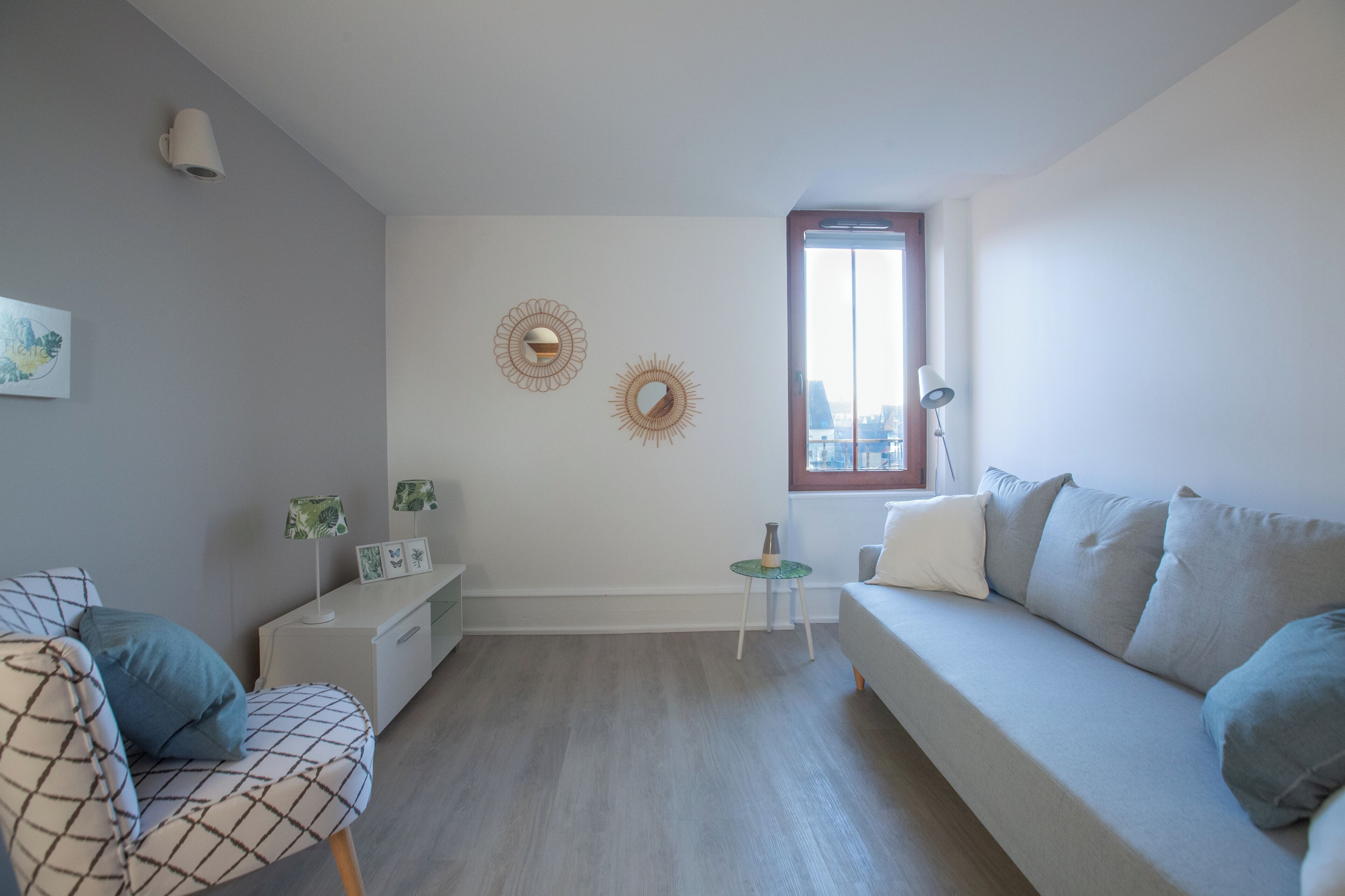 Una sala de estar moderna con un sofá, un sillón, una mesita y espejos decorativos en la pared.