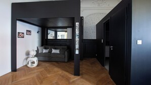 Een moderne woonkamer met een visgraatvloer, een grijze bank en een witte bijzettafel.