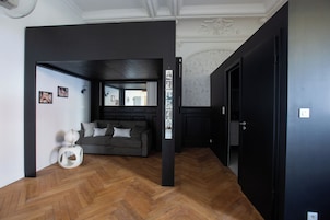Una sala de estar moderna con piso de espiga, un sofá gris y una mesita auxiliar blanca.