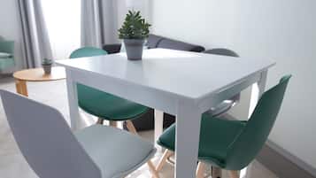 Un espace repas moderne avec une table blanche, des chaises vertes et une plante en pot.