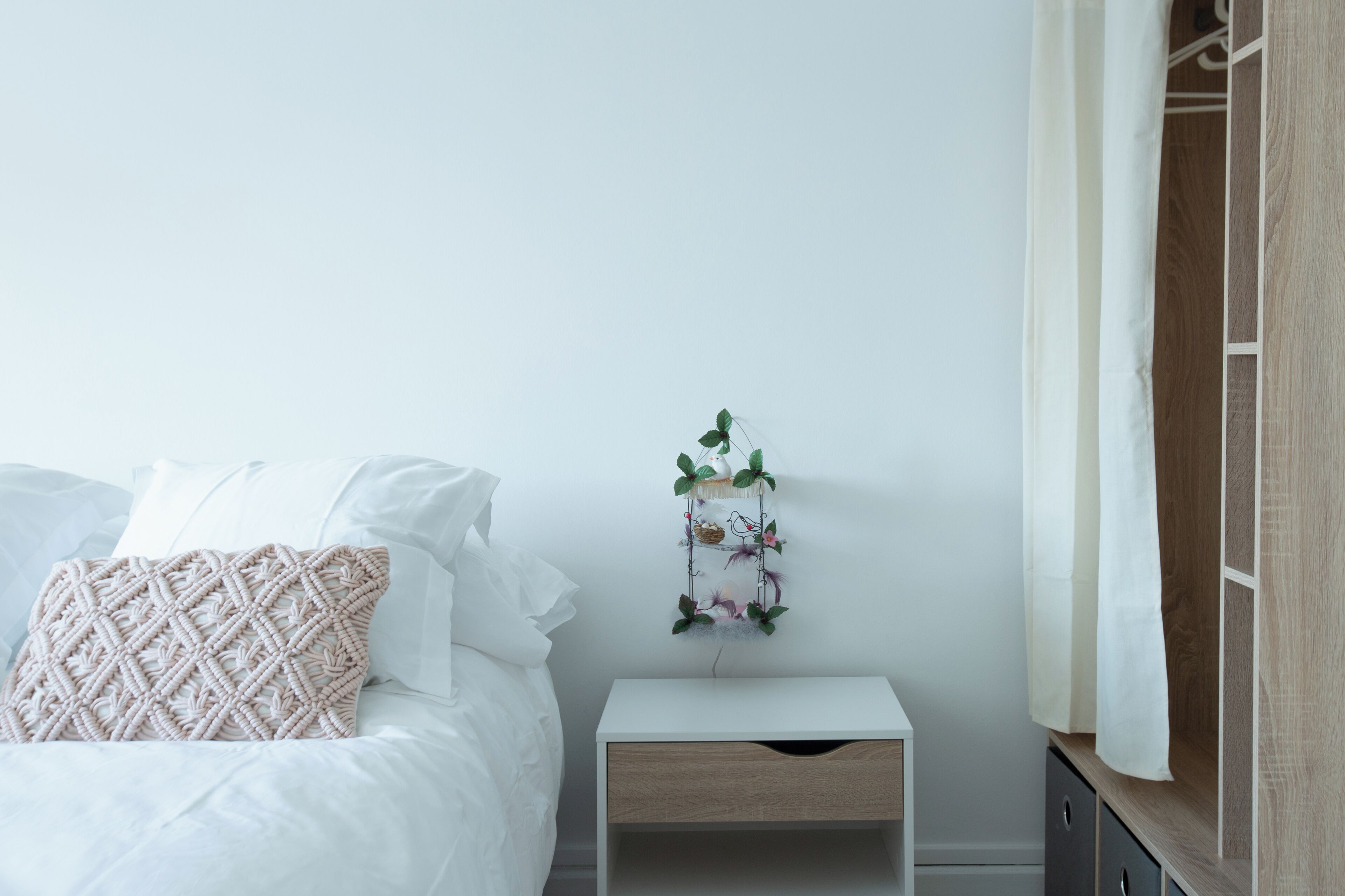 Une chambre à coucher bien rangée, avec un lit, une table de chevet et un élément décoratif fixé au mur.