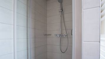 A shower with a handheld showerhead and a wall-mounted faucet.