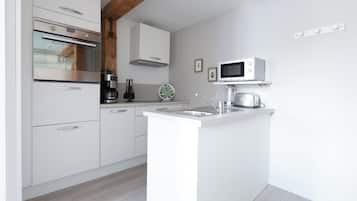 A modern kitchen with white cabinetry, a built-in oven, a microwave, and a coffee maker.