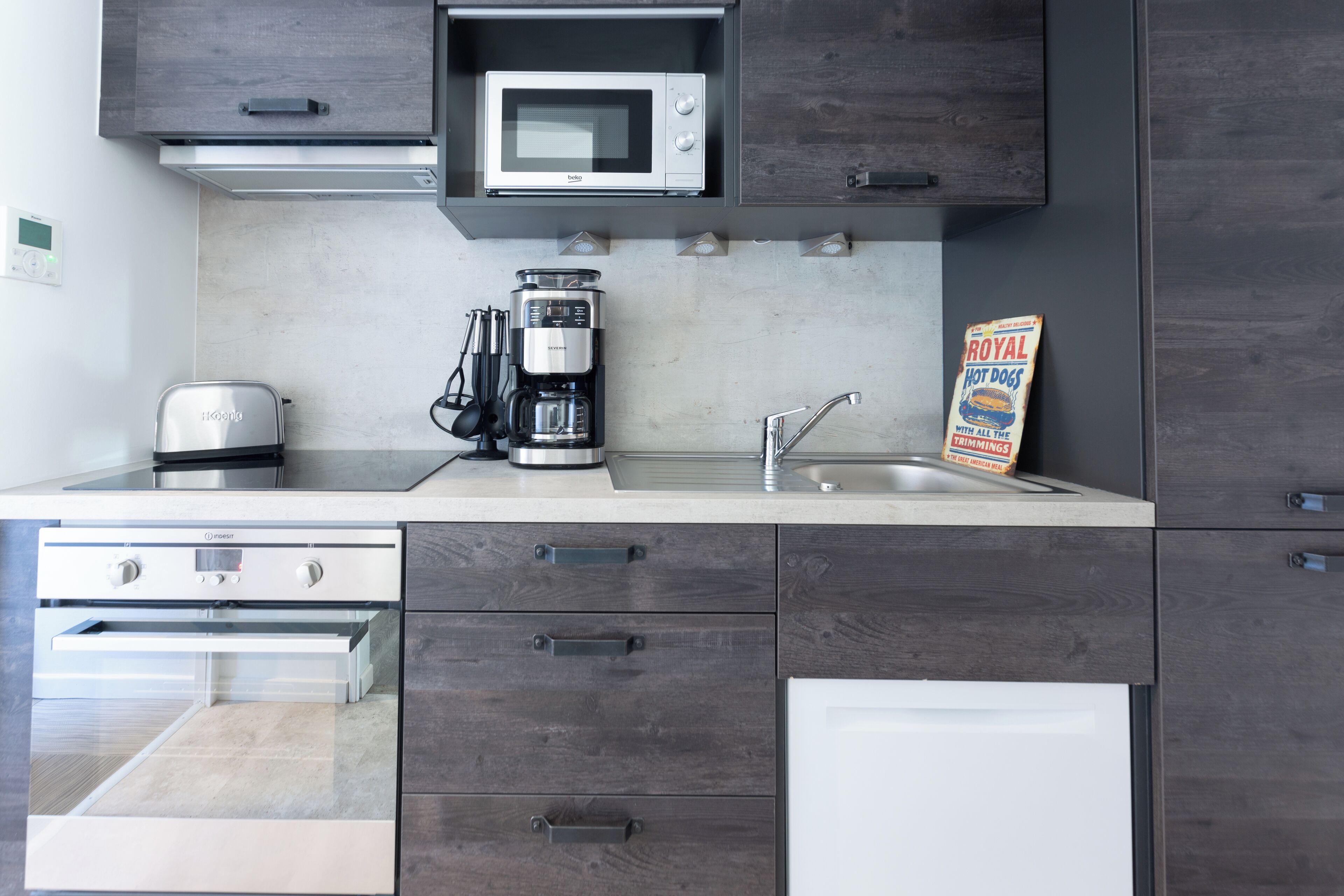Una cocina moderna equipada con microondas, cafetera y lavamanos.
