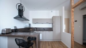 Een moderne keuken met een centraal eiland, barkrukken en een inbouwoven.
