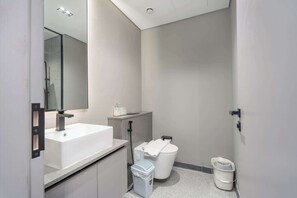 Une salle de bain moderne avec un lavabo blanc, un miroir et des toilettes.