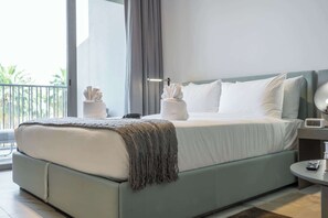 Une chambre d’hôtel moderne avec un grand lit, une table de chevet, une commode et une vue sur l’extérieur.