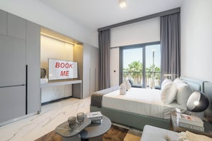A modern hotel room with a bed, a small table, a sofa, a TV, and a balcony with a view.