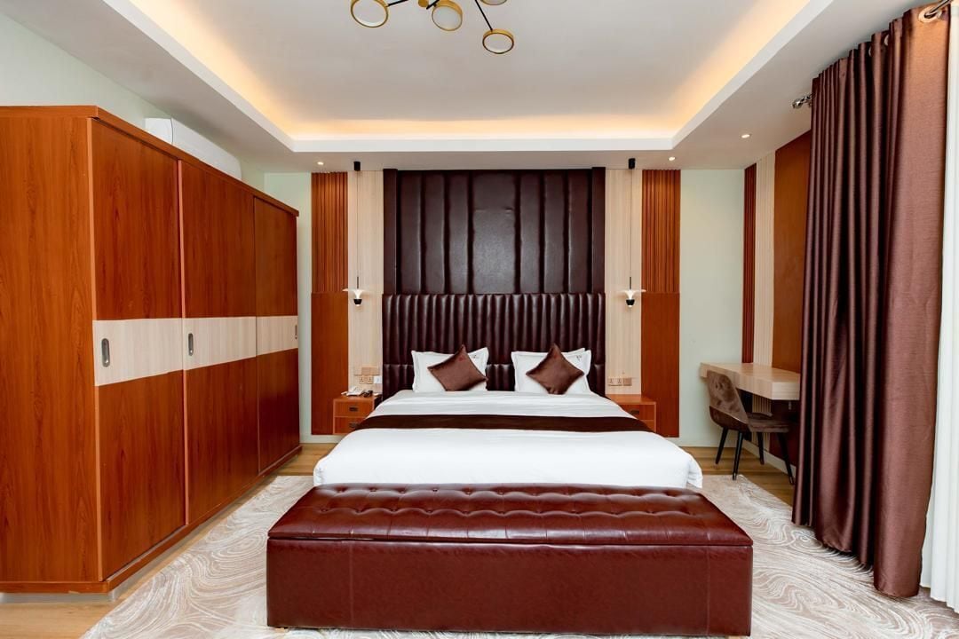 Une chambre à coucher moderne avec un grand lit, une armoire en bois et un bureau.