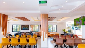 A modern dining area with yellow and brown chairs, a central column, and a large window in the background. - Kigali Delight Hotel (Kigali)