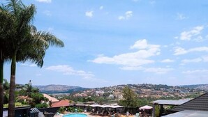 A swimming pool with a view of a town in the background. - Kigali Delight Hotel (Kigali)