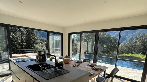 A modern kitchen with a large island, a dining area with a view of a pool and mountains, and large windows. - VILLA with private pool, near MONT VENTOUX and VAISON LA ROMAINE (Mollans-sur-Ouvèze)