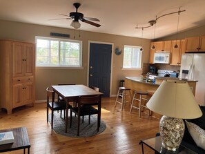 A kitchen with wooden cabinets, a dining table with chairs, a ceiling fan, and a kitchen island with stools.