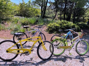 Three bicycles parked on a gravel path surrounded by greenery.