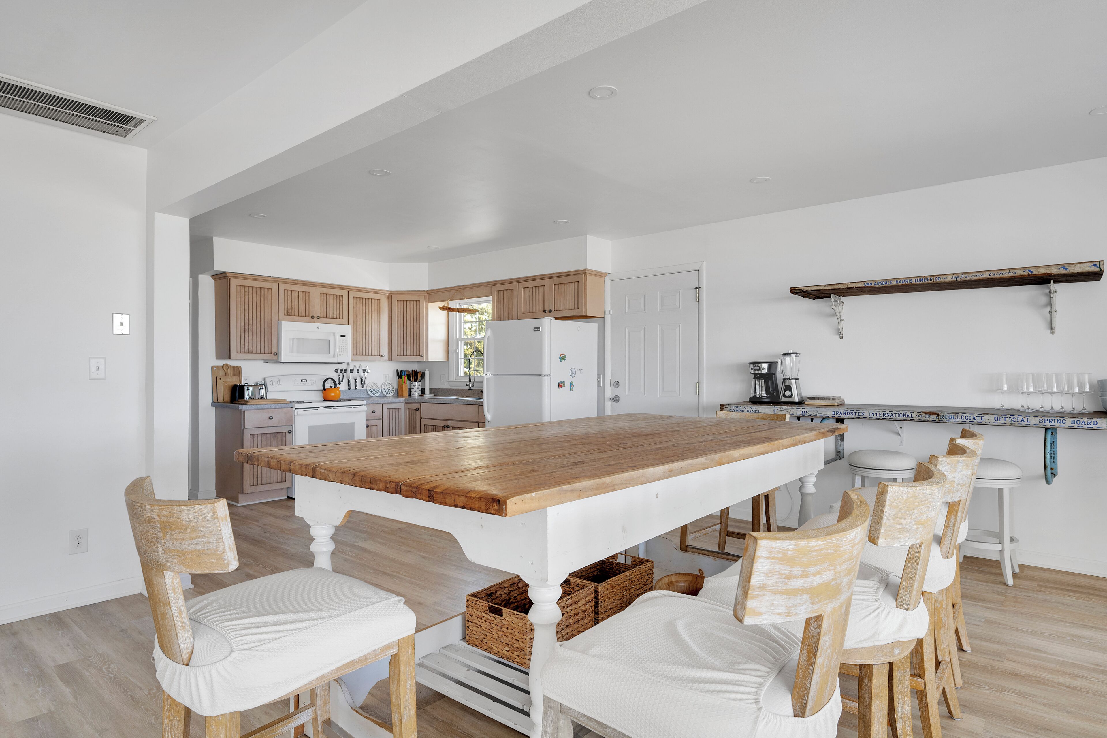 A modern kitchen with wooden cabinets, a large island, and white chairs.
