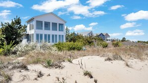 Una propiedad frente al mar con una casa grande de color blanco, con varias ventanas y un balcón.