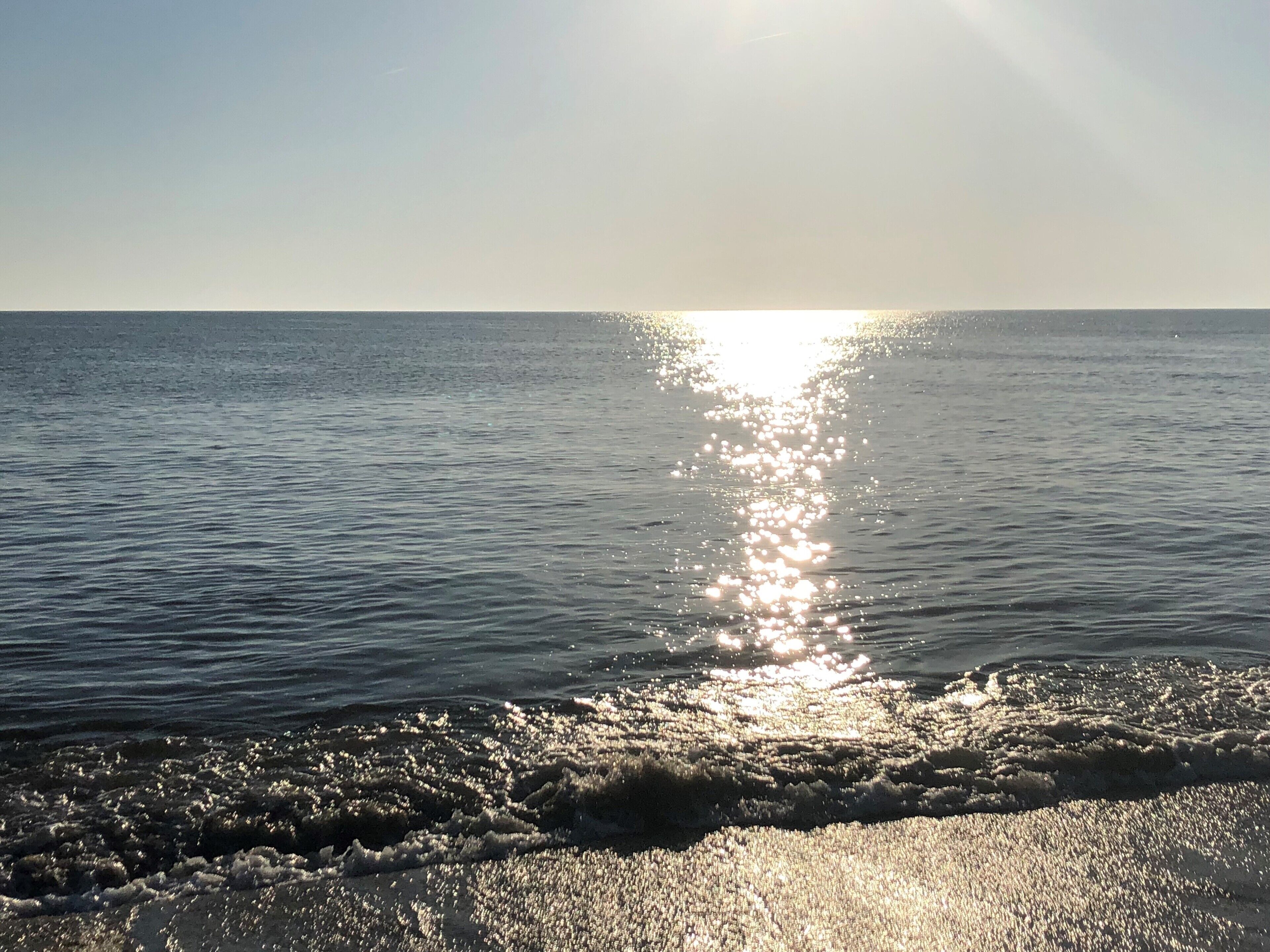 Une plage où la lumière du soleil se reflète sur l’eau.
