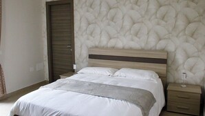 Une chambre à coucher avec un lit, une table de chevet, une porte en bois et un mur à texture.