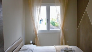 Une chambre à coucher avec un lit, une fenêtre avec des rideaux et une vue sur l’extérieur.