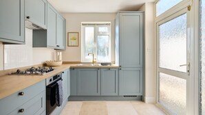 A modern kitchen with grey cabinets, a wooden countertop, and a large window. - The Randall Retreat Spacious 4bdr Home With Garden (London)
