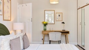 A bedroom with a bed, bedside table, lamp, desk, chair, and a mirror. - The Randall Retreat Spacious 4bdr Home With Garden (London)