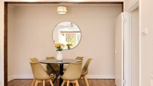A dining area with a round table, four chairs, and a vase with flowers. - The Randall Retreat Spacious 4bdr Home With Garden (London)