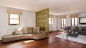 Ein modernes Wohnzimmer mit einer gebogenen Couch, einem Couchtisch und einem dekorativen Raumteiler.
