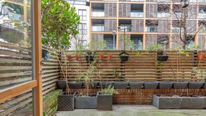 A courtyard with potted plants, a wooden fence, and a brick wall. - Cozy 2 Bedrooms, Devons Road DLR (London)