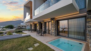 Ein modernes, zweistöckiges Haus mit Swimmingpool, Sitzgelegenheit im Freien und Blick auf die Landschaft.