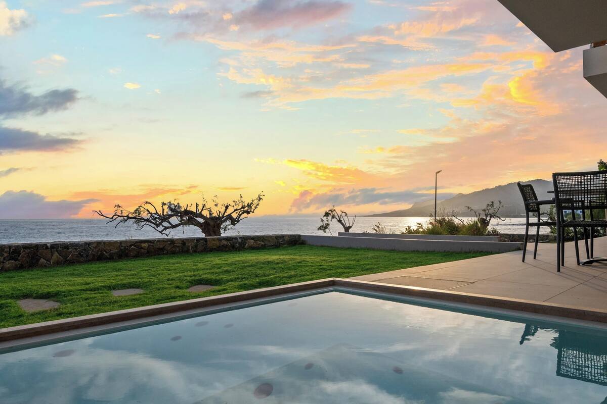A pool with a view of the ocean and sunset.