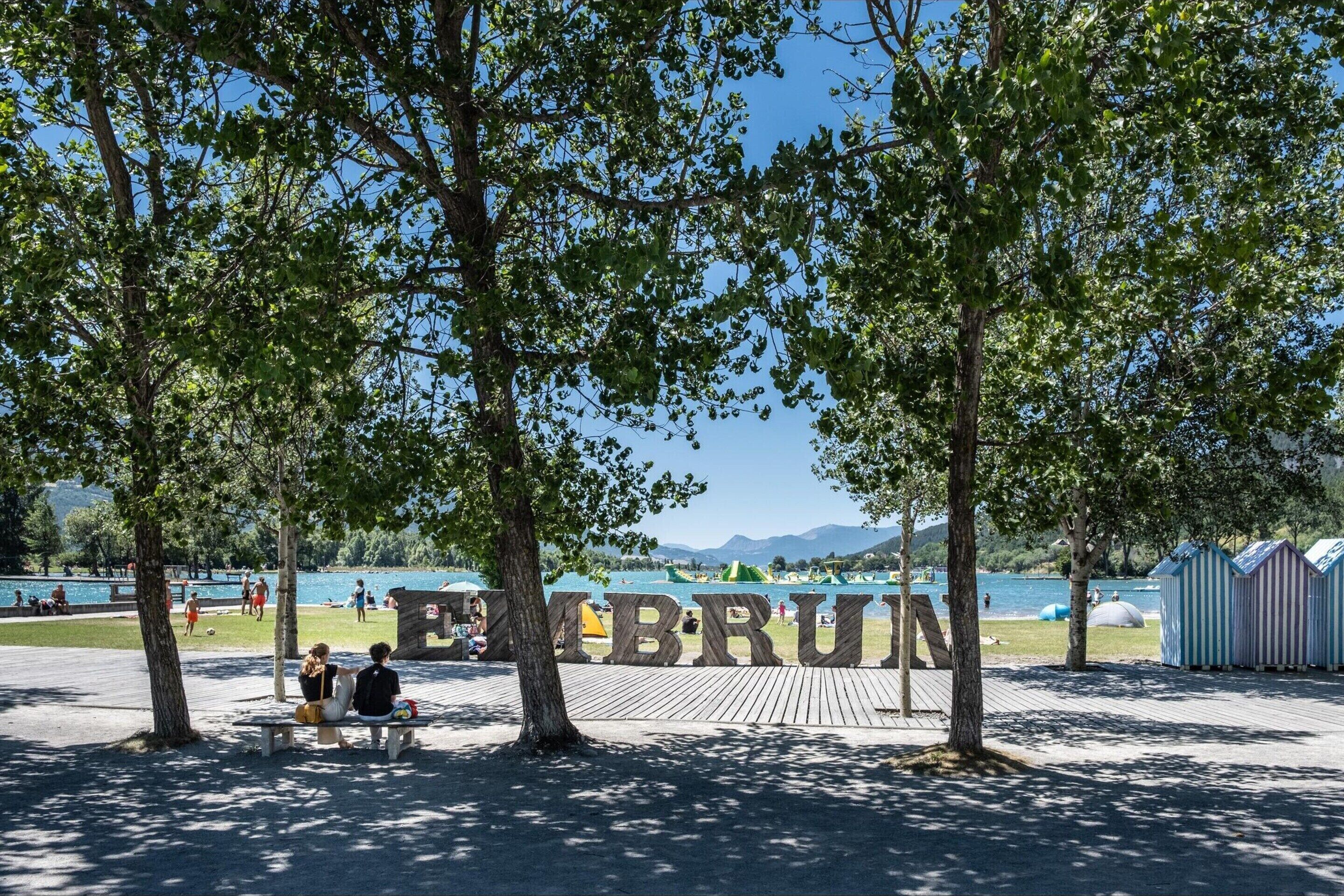 A park with a wooden bench, trees, and a lake.