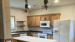 A kitchen with wooden cabinets, a white refrigerator, a microwave, and a stove.
