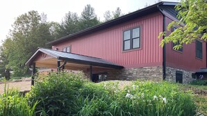 A red building with a stone foundation, a covered porch, and a landscaped garden with various plants and flowers.