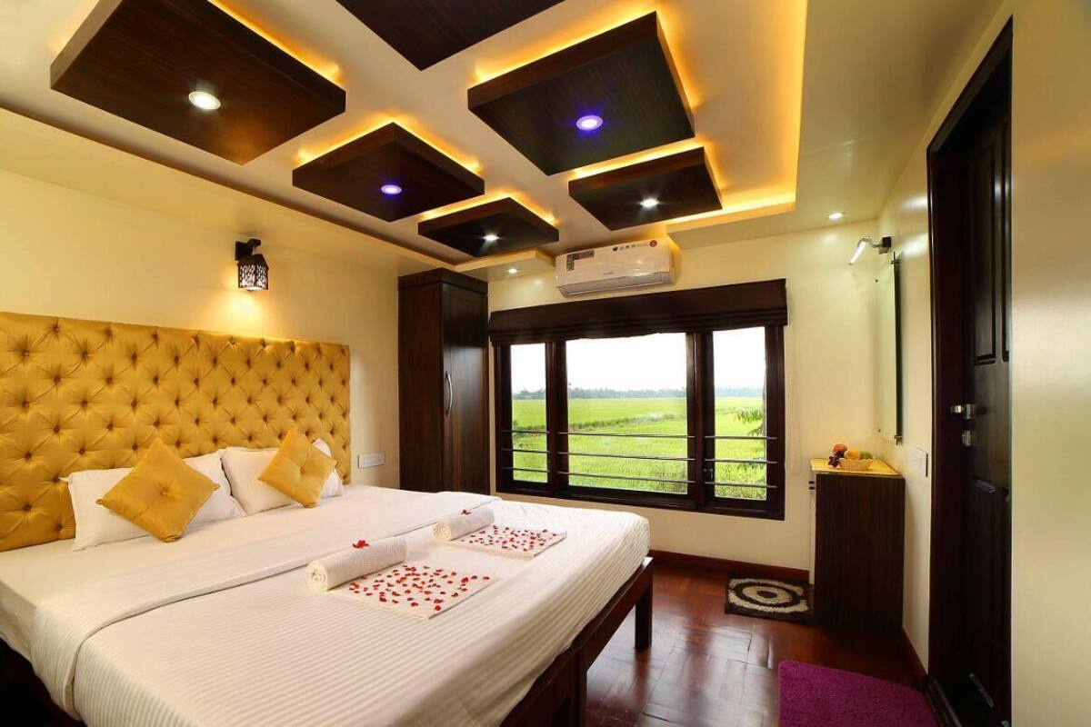 A bedroom with a large bed, a view of the outdoors, and modern ceiling design.