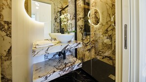 Un bany amb un lavabo de marbre, un mirall i una dutxa.