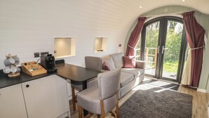 A cozy kitchen with a dining area, a coffee machine, and a wooden table. - The Hazel Hobbit Pod (Cowbridge)