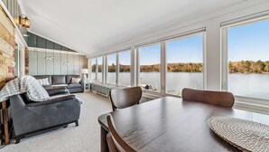 Een ruime kamer met een grote eettafel, een bank en uitzicht op een meer.